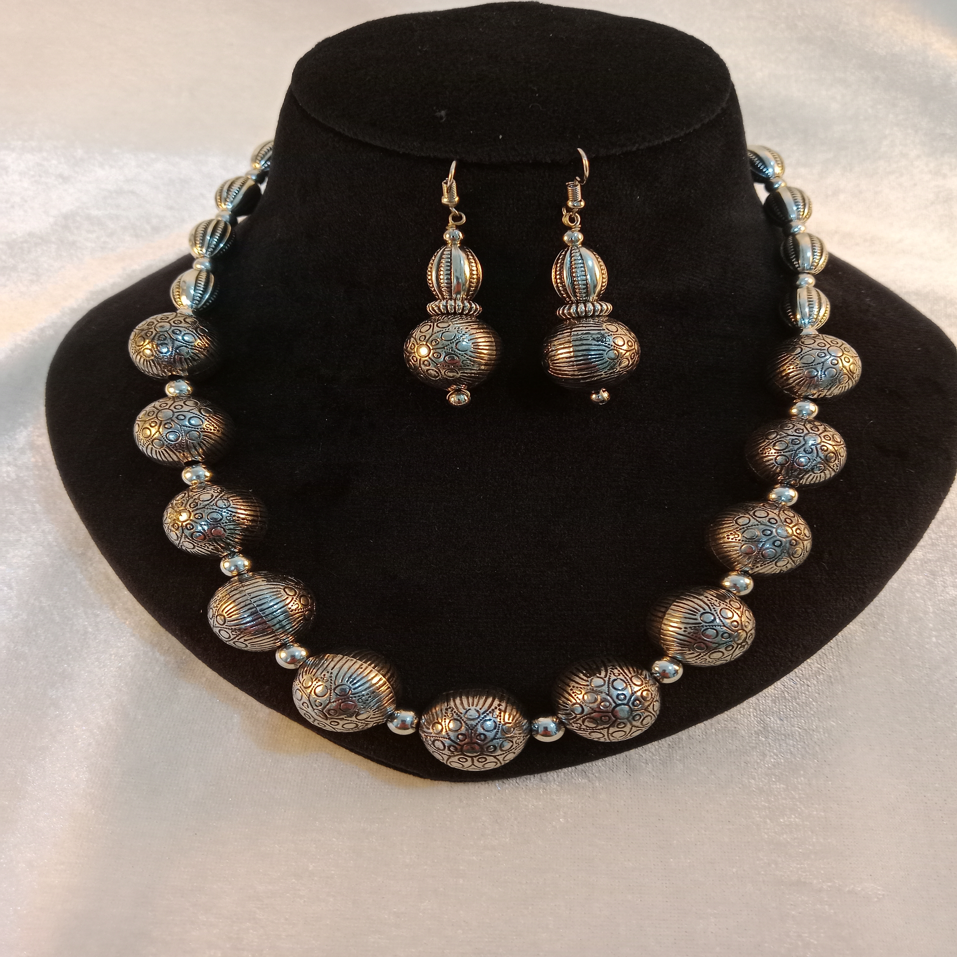 Oxidized necklace set with earrings on display stand – Blingso