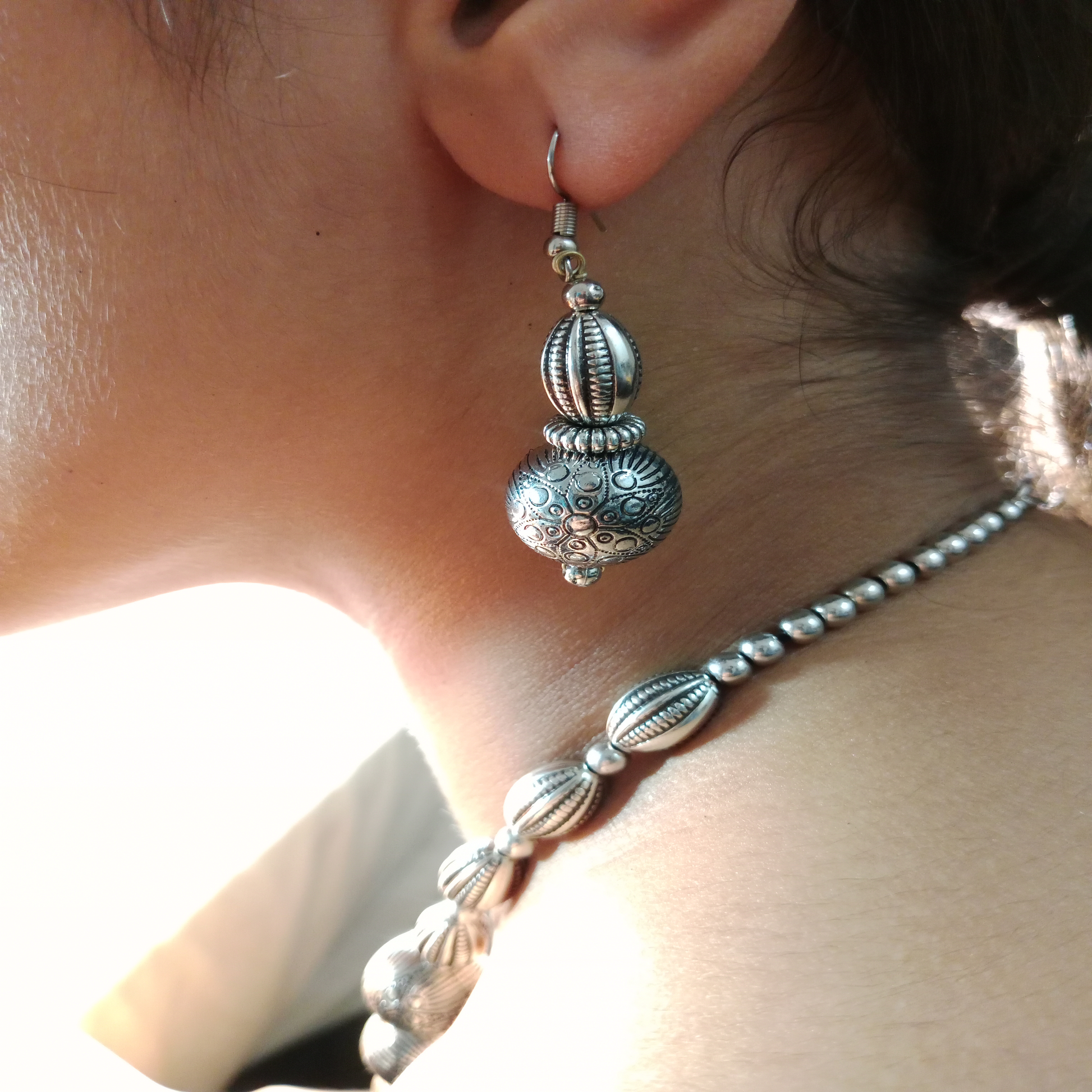 Close-up of oxidized earrings with beaded necklace – Blingso